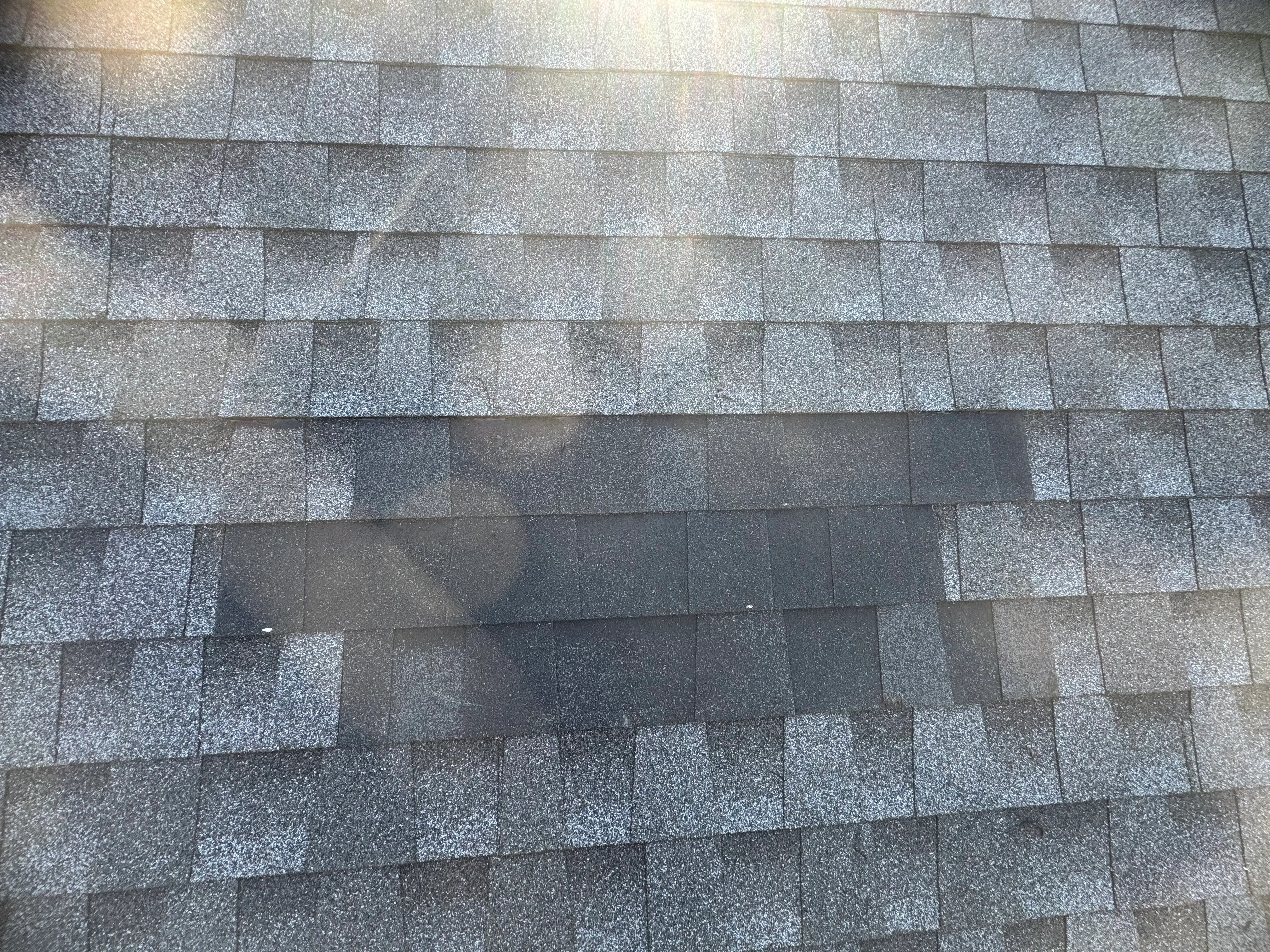 New asphalt shingle roof with charcoal, gray, and tan blend shingles installed in overlapping rows