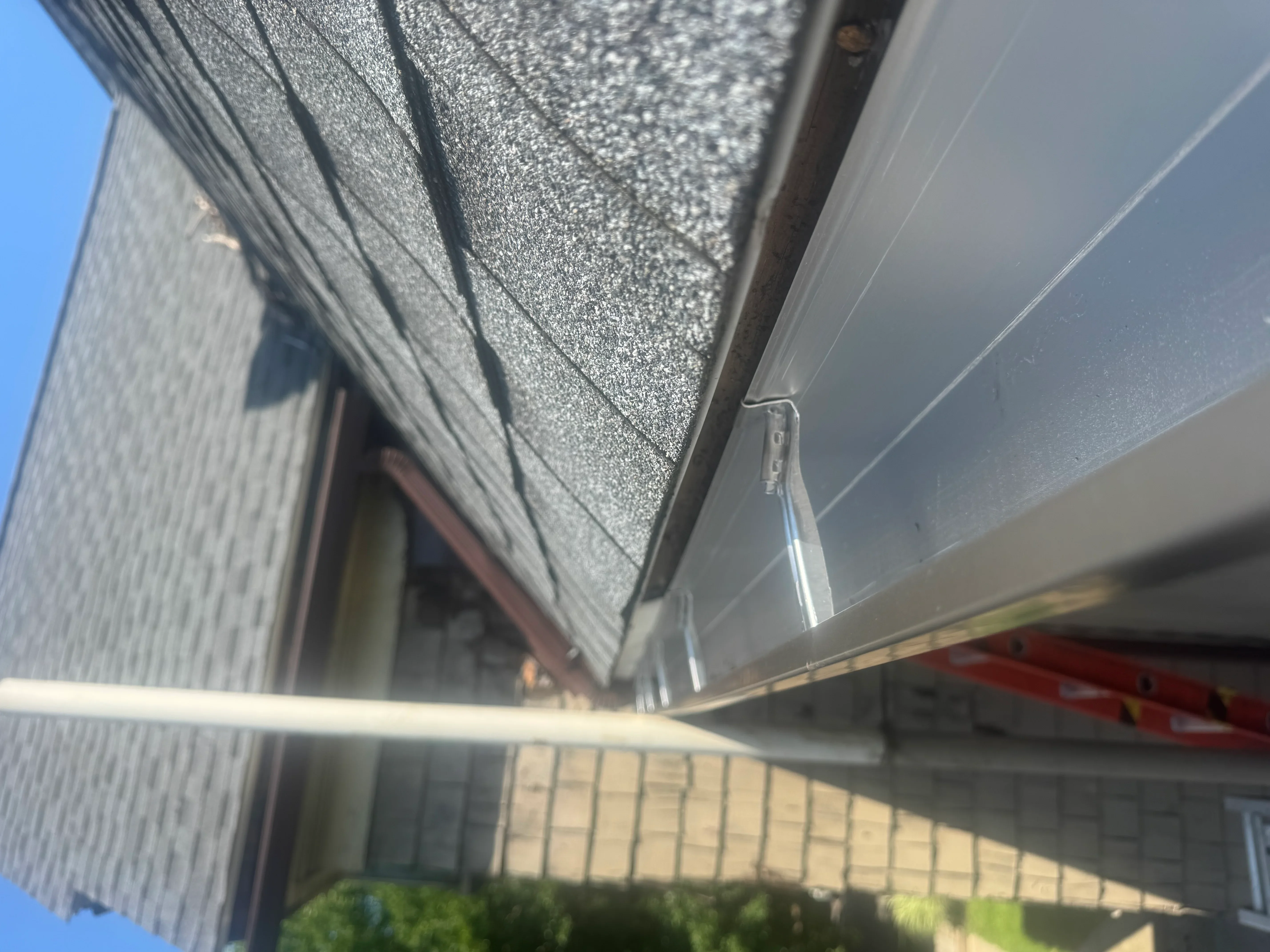 Gray asphalt shingles installed on pitched roof with metal flashing and soffit trim