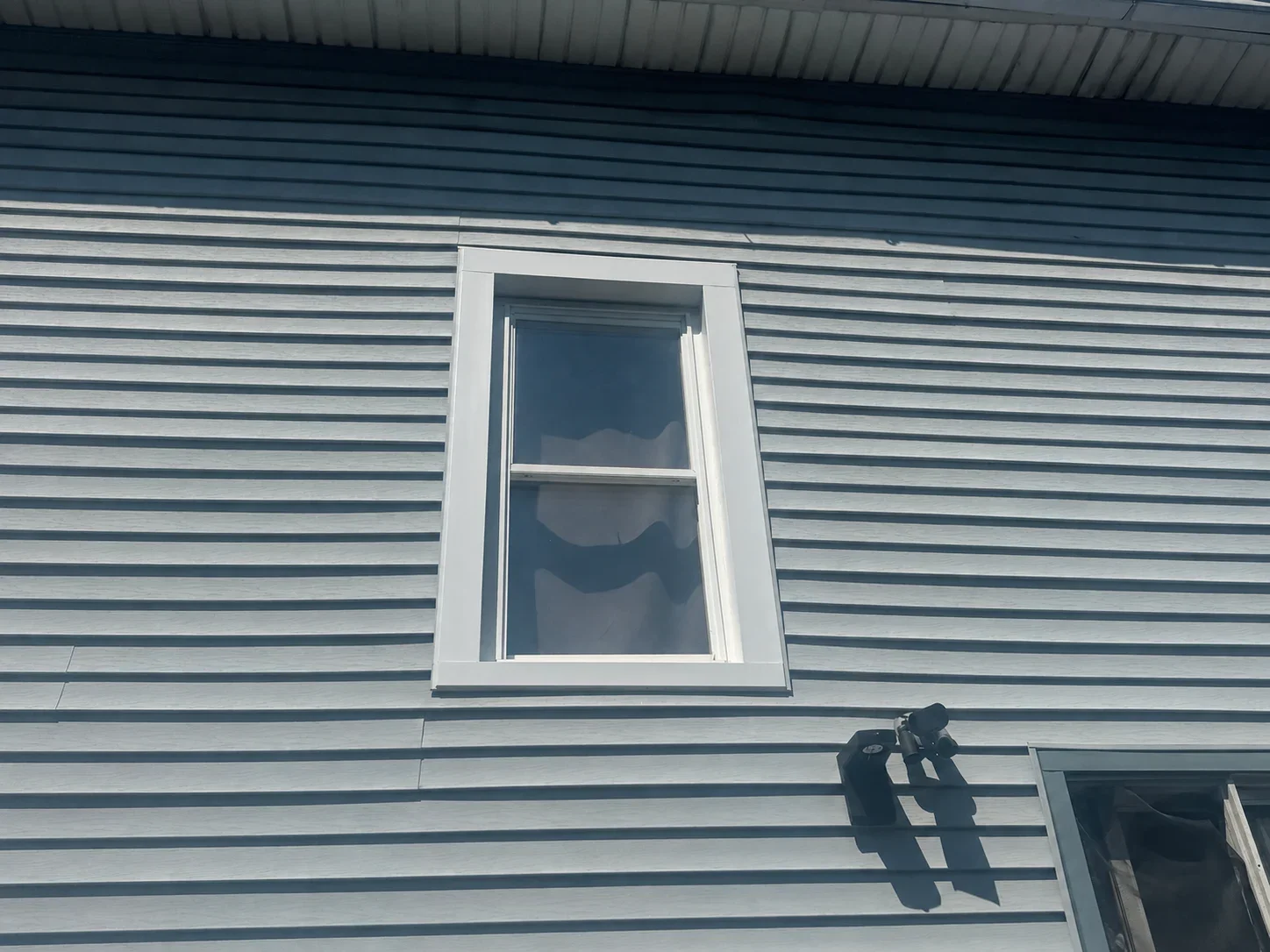Horizontal metal siding with white-trimmed double-hung window installation