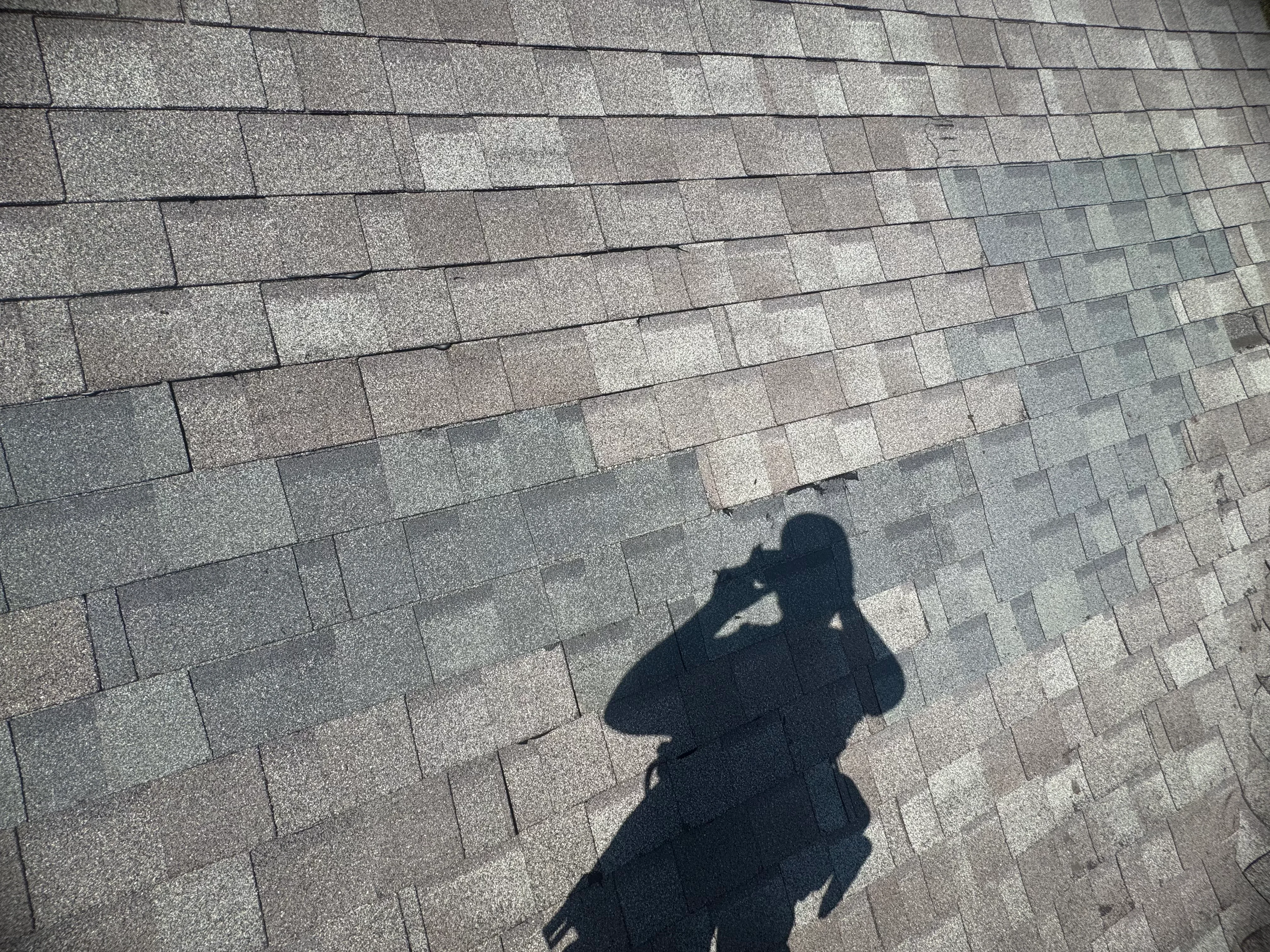 Newly installed gray asphalt shingles with staggered pattern and proper overlap on pitched roof