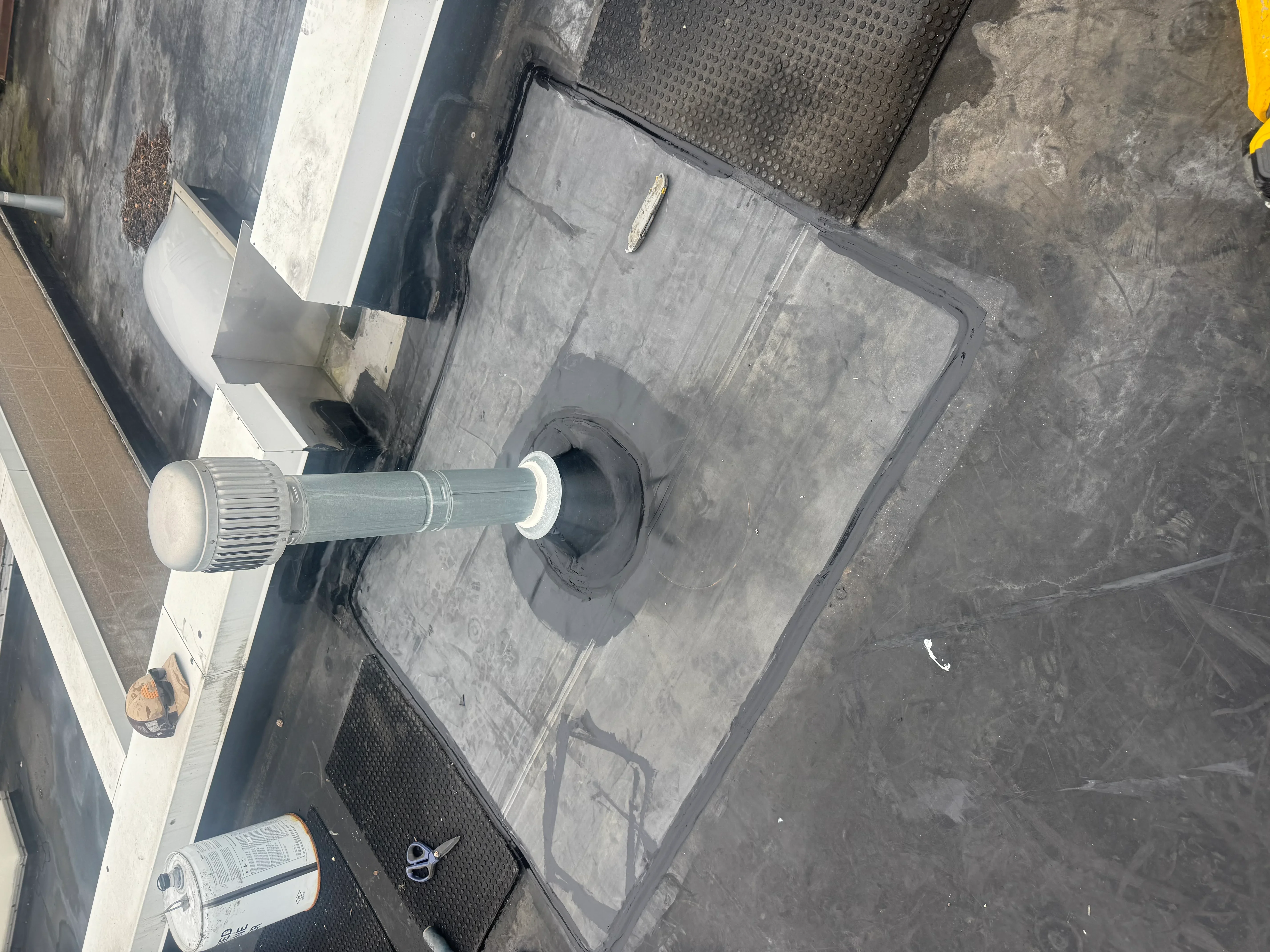 Metal roof vent with rubber boot and flashing installed on flat roof membrane